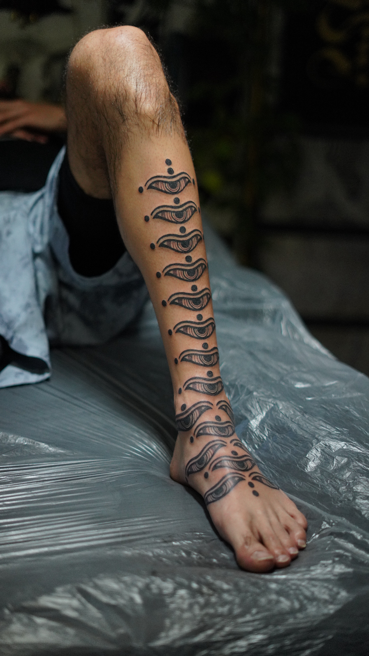 Repeating eye motif shin to foot tattoo by Steve Sherick